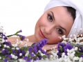 Beautiful young woman with towel on her head and flowers isolated on white