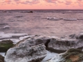 Icy stones near sea coast at sunset